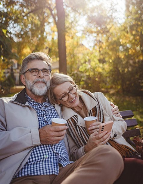 a man and a woman on a bench with coffee on their hands